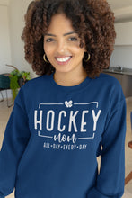 Charger l'image dans la galerie, Femme souriante portant un chandail bleu marine Impressions Gaspésie avec inscription Hockey Mom en blanc