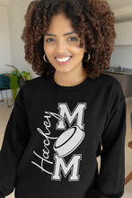 Charger l'image dans la galerie, Femme souriante portant un chandail noir Impressions Gaspésie avec inscription Hockey Mom et motif de rondelle