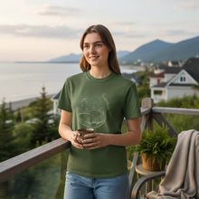 Charger l'image dans la galerie, Femme portant un t-shirt Impressions Gaspésie vert olive en coton épais avec un motif de phare sur une terrasse