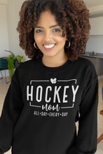 Charger l'image dans la galerie, Femme souriante portant un chandail noir Impressions Gaspésie avec inscription Hockey Mom en blanc
