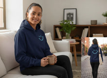 Charger l'image dans la galerie, Femme portant le hoodie bleu marine Impressions Gaspésie avec motif sourire sur la poitrine et dans le dos

