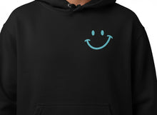 Charger l'image dans la galerie, Hoodie noir Impressions Gaspésie avec un petit motif de sourire bleu clair sur la poitrine, style décontracté.
